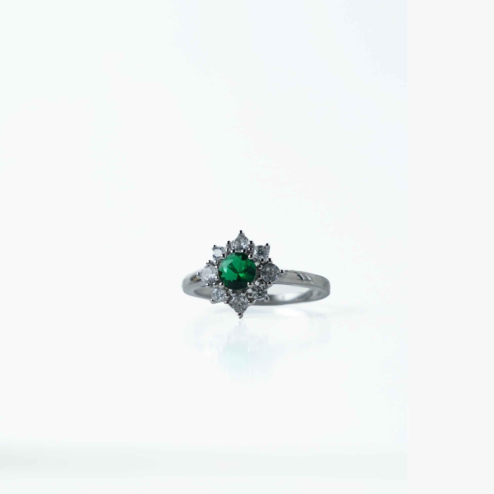 Elegant and timeless, this Sterling Silver 925 Emerald &amp; Diamond Halo Ring features a stunning green stone at its center, surrounded by a sparkling halo of white stones. Its vintage-inspired design adds a royal touch to any look.